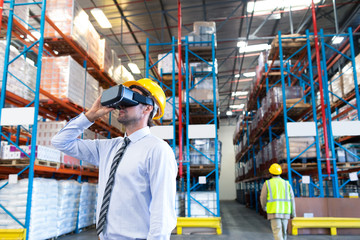 Male supervisor using virtual reality headset in warehouse