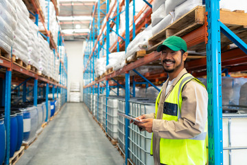 Male worker holding digital tablet and looking at camera in warehouse