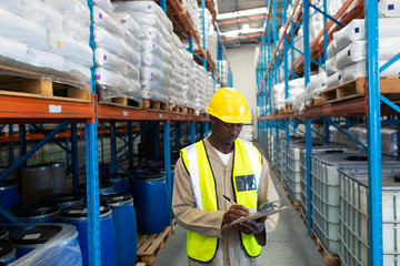 Male worker writing on clipboard in warehouse