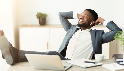 Naklejka premium Cheerful worker listening his favorite music in earphones at office.