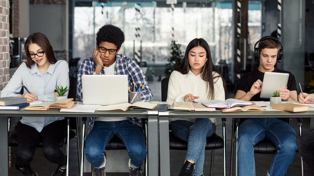 Students using different gadgets studying in library