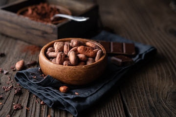 Healthy snack, superfood unroasted cocoa beans in a wooden bowl