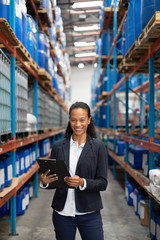 Female manager holding clipboard in warehouse