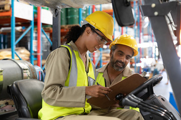 Male and female staff discussing over clipboard in warehouse