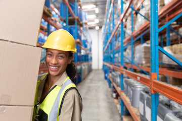 Female staff carrying cardboard boxes in warehouse