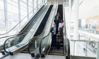 Diverse business travellers coming down an escalator
