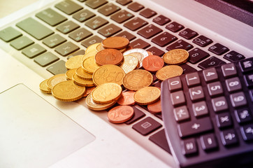 coins on laptop keyboard and calculator close-up. Business concept.