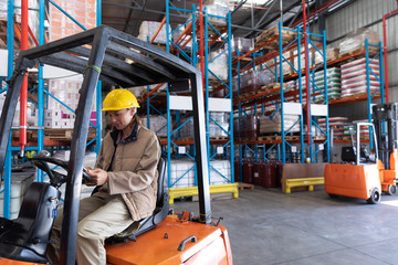 Female worker using digital tablet while sitting in forklift in warehouse © wavebreak3