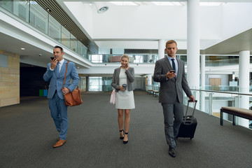 Business people talking on mobile phone while walking in the corridor