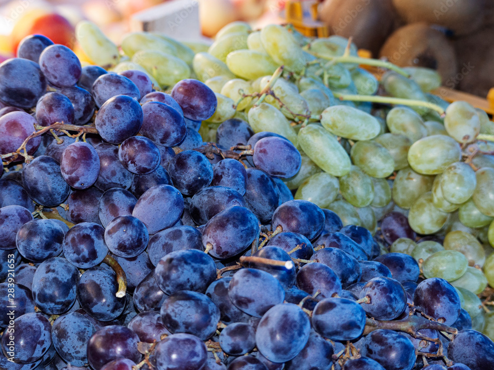 Poster blue and green grapes lie on a store counter. colorful background of different grape varieties