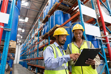 Male and female worker discussing on clipboard in warehouse