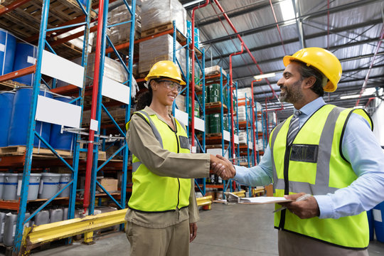 Male and female staff shaking hands with each other in warehouse