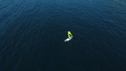 Windsurf woman alone in the blue sea. Windsurfing on the surface of the water