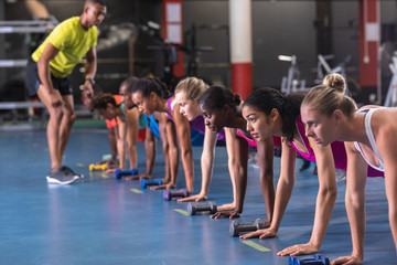 Obraz premium Male trainer training people to perform exercise in fitness center