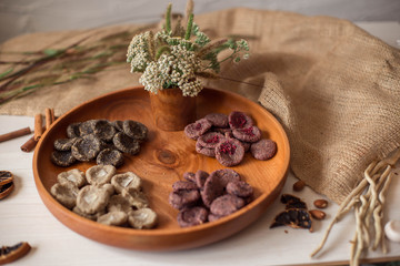 Assortment of sweets without sugar and gluten on a wooden dish. Dessert made from healthy natural ingredients. Beautiful composition of healthy diet candies and flowers