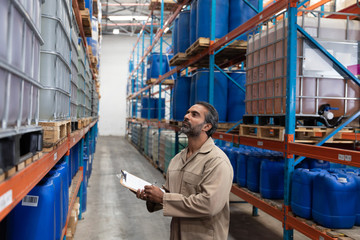 Male staff writing on clipboard while checking stocks