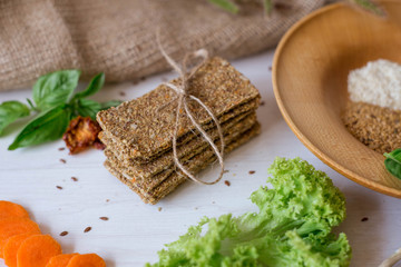 Crispbread tightened by a rope. Healthy food on a white background besid the ingredients in a wooden plate. .Lettuce with carrot near bread cakes