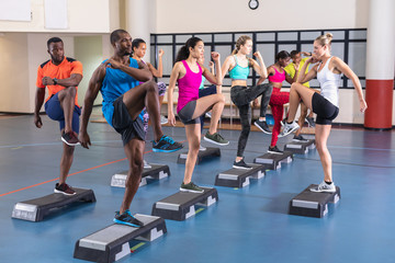 Female trainer training people to exercise on aerobic stepper