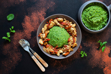 Mashed potatoes with green peas and corn served with chicken and vegetable stew. African cuisine, Kenyan cuisine, a traditional dish called mukimo. Top view, copyspace