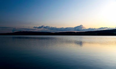 view of the lake at dawn early in the morning, silhouettes of hills and clouds