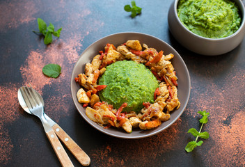 Mashed potatoes with green peas and corn served with chicken and vegetable stew. African cuisine, Kenyan cuisine, a traditional dish called mukimo or irio. Close-up
