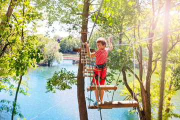 Little boy walk on the rope bridge between trees