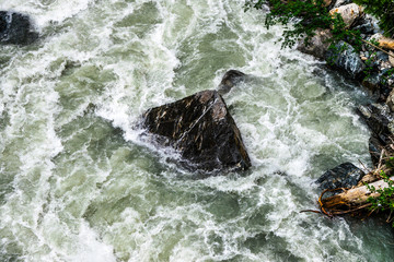 the water of the stormy mountain river flowing among stones and boulders