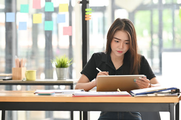 Young freelancer woman working while using pen and tablet.