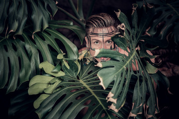Young male hiding between tropical plants