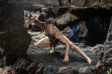 Muscular male with painted face in cave