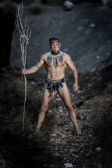 Handsome male in loincloth standing with stick