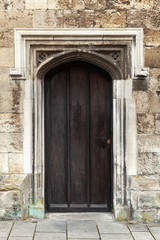 Fototapeta na wymiar Closed black wooden door in old stone wall