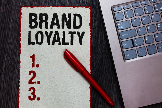 Handwriting text writing Brand Loyalty. Concept meaning Repeat Purchase Ambassador Patronage Favorite Trusted Piece paper red borders black marker computer keyboard wooden background