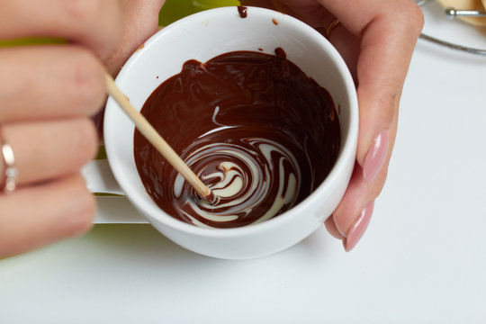 Woman Prepares Icing From White And Black Chocolate. For Glazing A Dessert