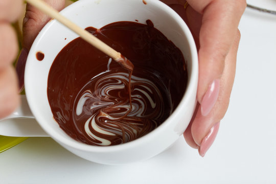 Woman Prepares Icing From White And Black Chocolate. For Glazing A Dessert