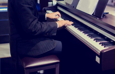 Close-up of a music performer's hand playing the piano. Side view of instrument musical tool. Close up to the piano keyboard background with selective focus.