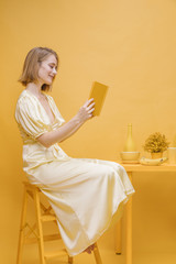 Portrait of woman reading a book in a yellow scene