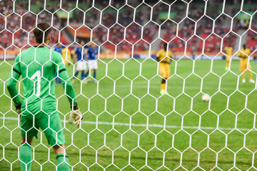 Net in soccer goal with goalkeeper and striker behind before penalty shoot.