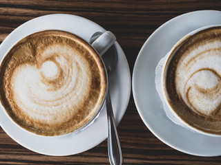 Two cups of coffee on wooden rustic background with beautiful latte art