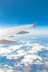 Aircraft wing on the clouds, flies on the mountains background