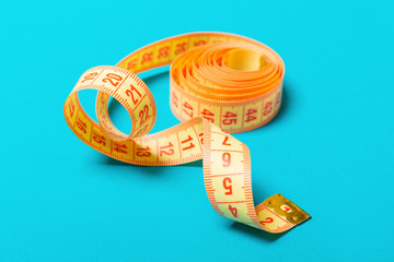 Close up of tangled measuring tape on blue background. Fitness and healthy diet concep with perspective view