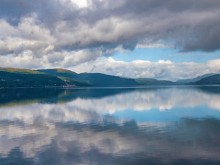 The sky with clouds is reflected in the water of the fjord, Norway