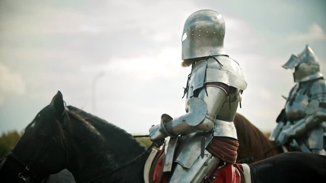 A man knight in the armor riding a horse - another knight comes next to him