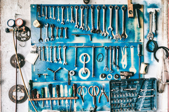 The variety of grunge rusty car garage tools hangs on a wall. Vintage retro tone.