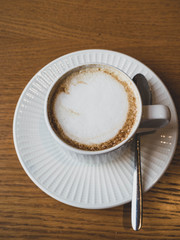 Cappuccino or latte in white cup. Wooden rustic background. Copy space for your text