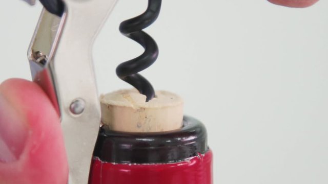 Someone's opening up a bottle of corkscrew wine. Macro shooting of the opening of the bottle with a cork. The cork is being pulled out with a corkscrew.