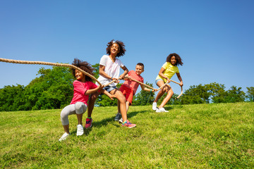 Team kids game of pulling rope in summer camp