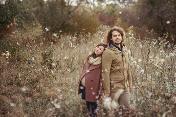 Fototapeta na wymiar Young happy caucasian couple expecting a baby. Pregnant woman and her husband walking and having fun together outdoors in the autumn. Family, parenthood, love, happiness concept.