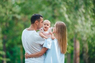 Fototapeta premium Young beautiful woman, handsome man and small cute daughter outdoors. Blurred green background