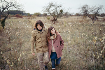 Young happy caucasian couple expecting a baby. Pregnant woman and her husband walking and having fun together outdoors in the autumn. Family, parenthood, love, happiness concept.